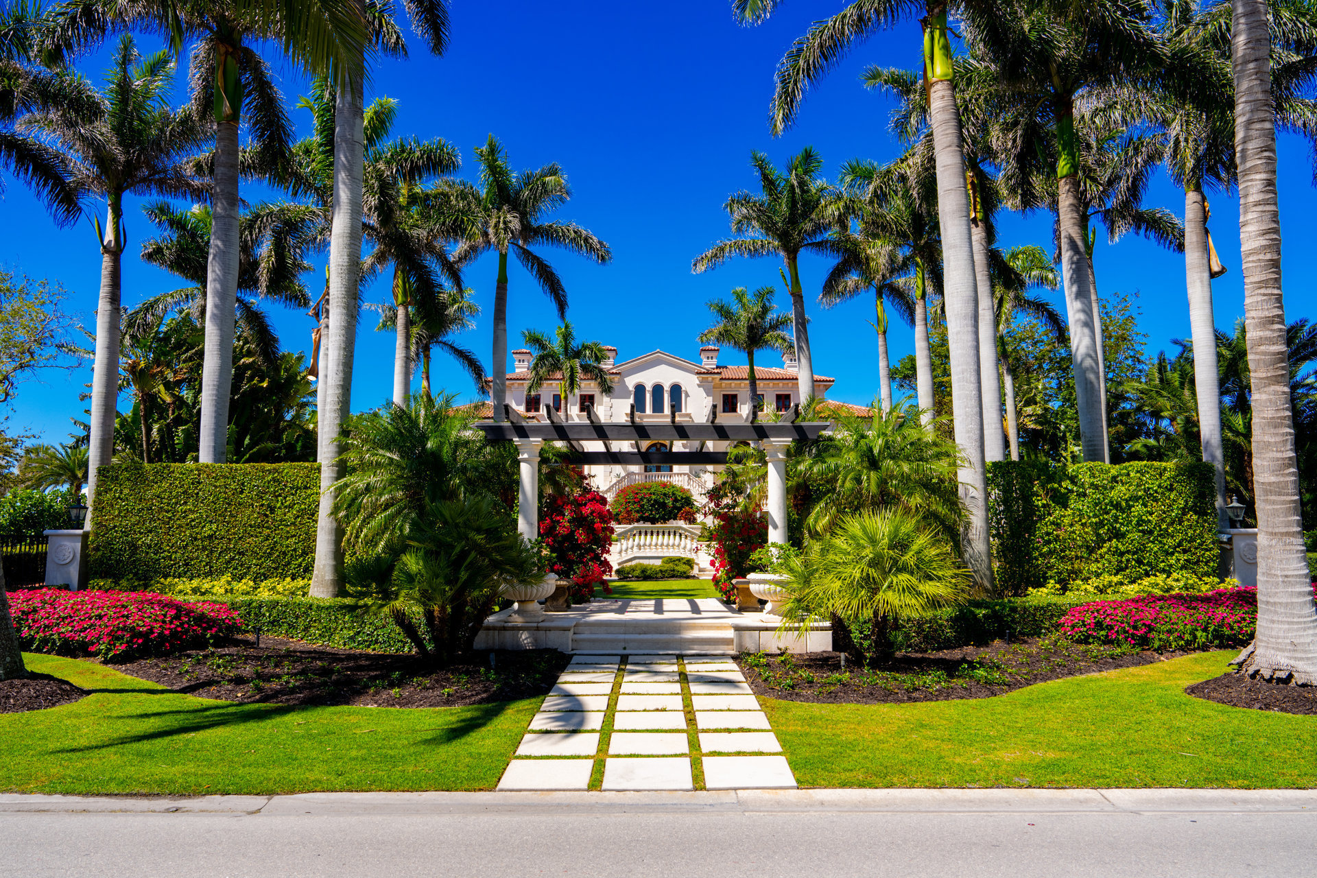 Luxury South Florida mansion with immaculate striped lawn, tropical landscaping, palm trees, and premium curb appeal at sunset